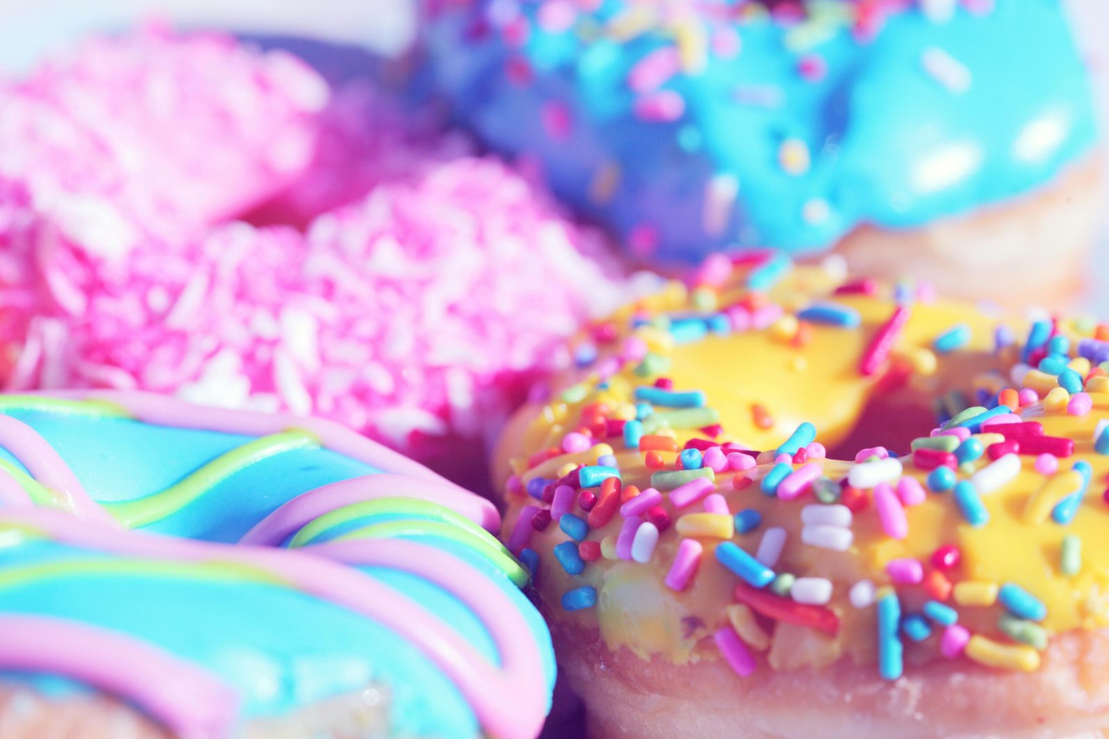 Close-up of assorted donuts with colorful icing and sprinkles, showcasing sweet indulgence.