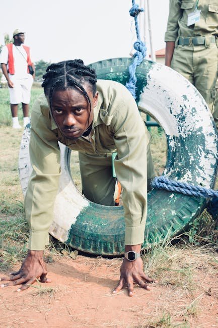 Young man with dreadlocks crawling through an outdoor tire obstacle in Sagamu, Nigeria.