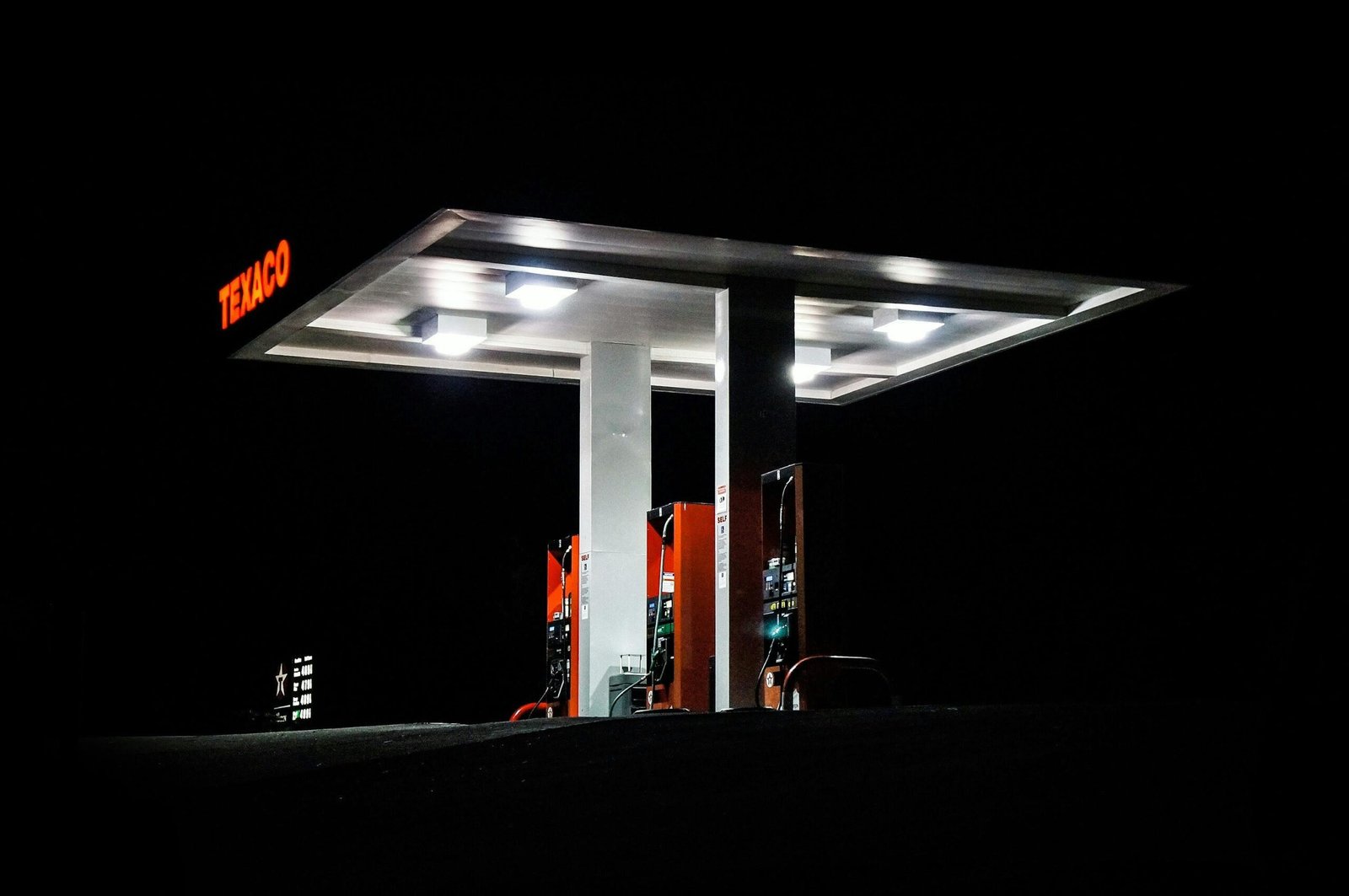 Night view of a Texaco gas station brightly illuminated with fuel pumps visible against a dark backdrop.