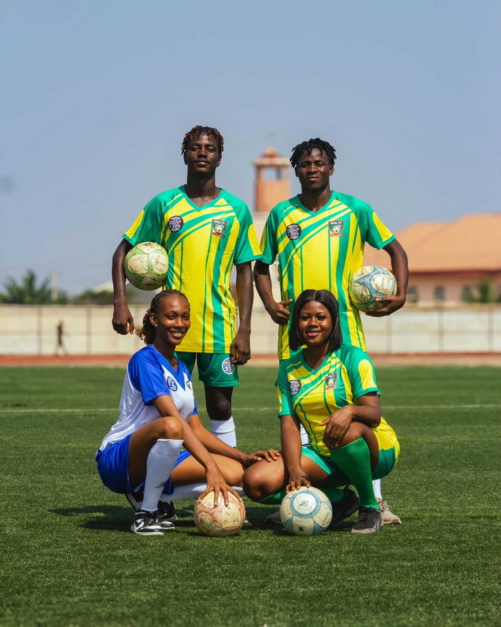 Group of young soccer players in team uniforms posing confidently on a sunny day.